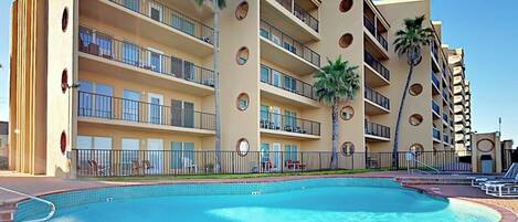 Ein Hotel mit Schwimmbad, mehreren Balkonen und Palmen.