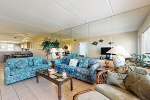 A living room with a sofa, armchairs, a coffee table, and a television. - Suntide II Condominiums #207 (South Padre Island)