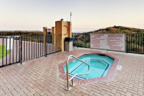 A swimming pool with a metal ladder, surrounded by a brick patio and a metal fence. - Suntide II Condominiums #207 (South Padre Island)