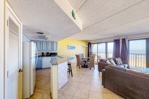 A spacious living area with a kitchen, a dining table, and a sofa. - Florence II Condominiums #201 (South Padre Island)