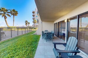 Un balcon avec une table et des chaises, une pelouse et des palmiers.