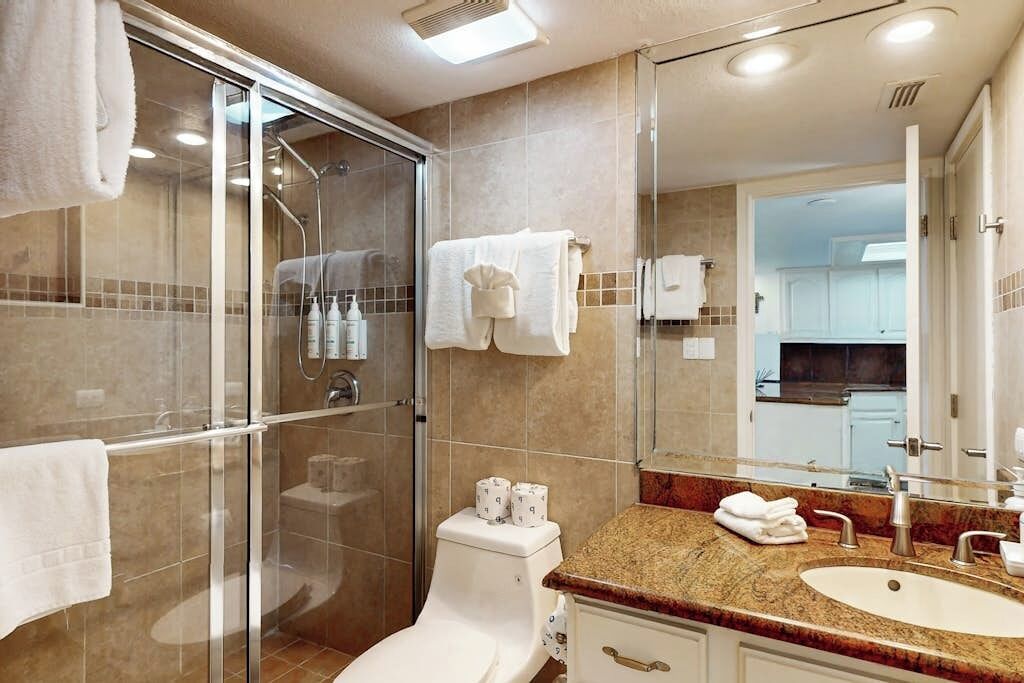 Une salle de bain moderne avec une douche à parois de verre, des toilettes, un lavabo et un miroir.