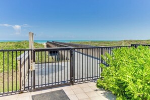 A gated entrance to a beach area with a clear view of the ocean and a pathway leading to a building. - Ocean Vista Condominiums #102 (South Padre Island)