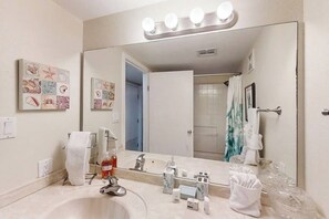 Une salle de bain dotée d’un grand miroir, d’un meuble-lavabo et d’un espace douche.
