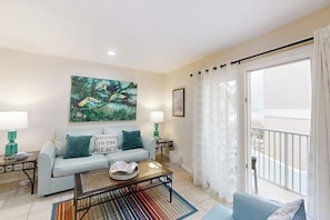 A living room with a sofa, coffee table, and artwork on the wall. - La Internacional Condominiums #210 (South Padre Island)