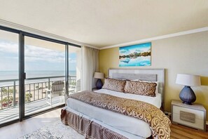 A bedroom with a large bed, a nightstand, a lamp, and a painting. - San Luis Paradise #930 (Galveston)