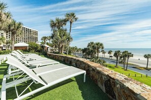 A hotel with a pool area, palm trees, and a view of the beach. - San Luis Paradise #930 (Galveston)