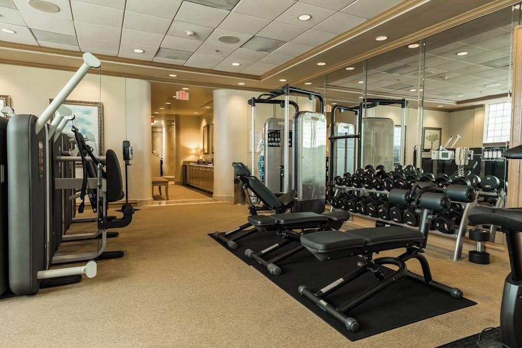 A gym with exercise equipment, weight benches, and dumbbells.