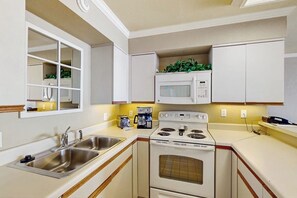 A kitchen with a double sink, a microwave, a stove, and cabinets. - San Luis Paradise #930 (Galveston)