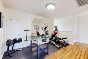 A gym with exercise equipment, a foosball table, and a mirror. - Cabana Cove - Channel-Front, Game Room & Kayaks (Corpus Christi)