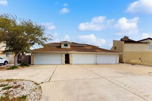 A two-story house with a garage, a tree in the front yard, and a clear sky. - Cabana Cove - Channel-Front, Game Room & Kayaks (Corpus Christi)