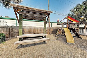 Un parque infantil con un tobogán y una mesa de picnic.