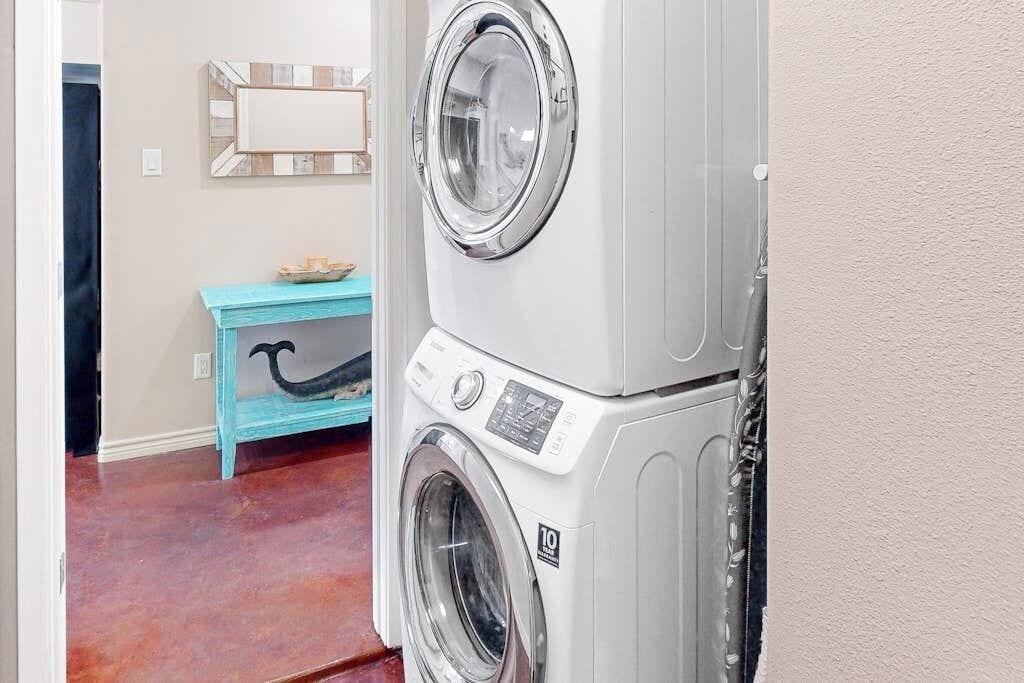 Een wasserette met gestapelde wasmachines, een blauwe bank en een spiegel aan de muur.