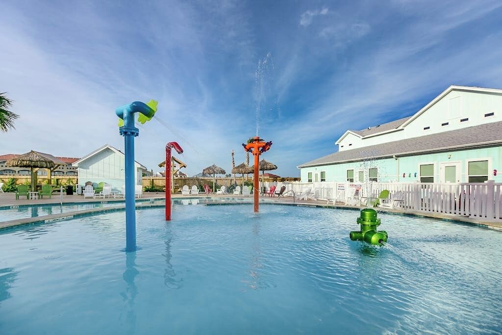 Una piscina con varios juegos de agua, incluyendo una fuente y un chorro.