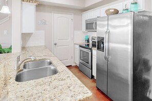 Una cocina con electrodomésticos de acero inoxidable, un lavamanos doble y un microondas.