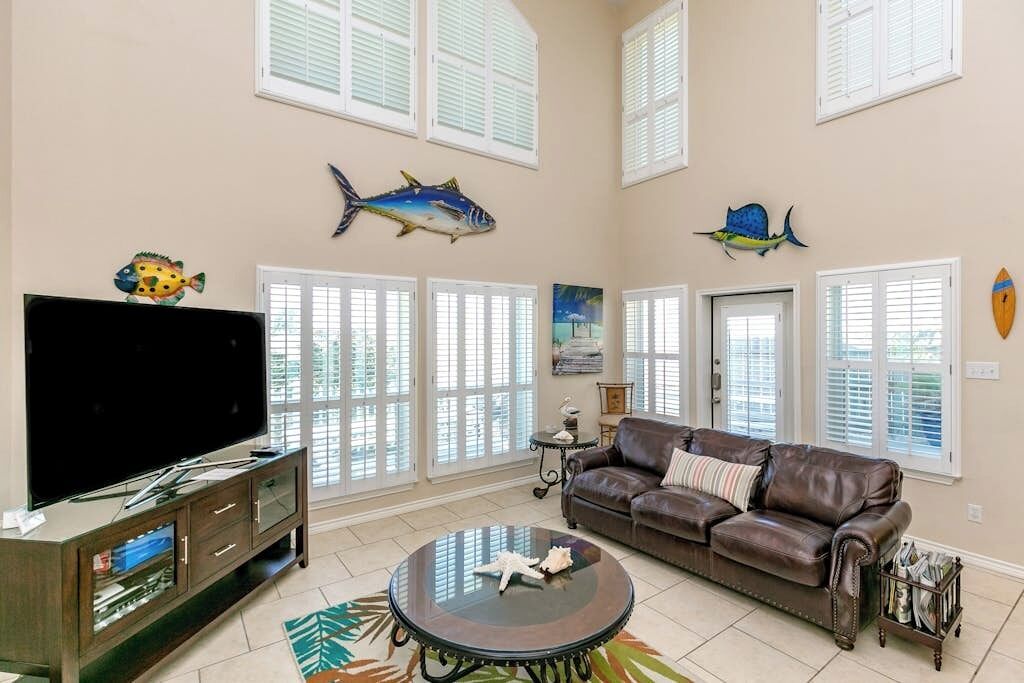 Un salon doté d’un téléviseur à écran plat, d’un canapé en cuir et de poissons décoratifs accrochés au mur.