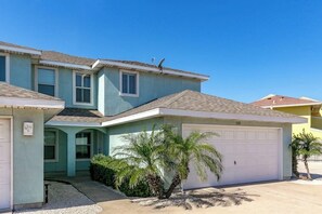 A two-story house with a garage, a satellite dish, and a palm tree in the front yard. - NPI Hideaway Stay - Shared Pool, Near the Beach (Corpus Christi)