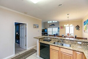 A kitchen with granite countertops, a dishwasher, and wooden cabinets. - NPI Hideaway Stay - Shared Pool, Near the Beach (Corpus Christi)