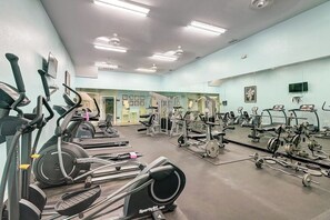 Et fitnesscenter med forskellig træningsudstyr, herunder løbebånd, spinningcykler og styrkemaskiner.