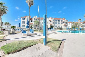 Ein Resort mit Schwimmbad, Liegestühlen und Palmen.