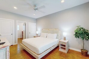 Ein Schlafzimmer mit einem Bett, Nachttischen, einem Deckenventilator und einer Topfpflanze.