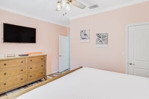 Ein Schlafzimmer mit einem Bett, einem Schminktisch, einem Fernseher und Bildern an der Wand.