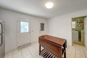 Ein Zimmer mit einer hölzernen Bank, weißen Wänden, einer Tür und einem Fenster.