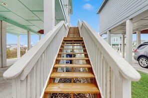 A wooden staircase with white railings leading to a covered area with a car parked nearby. - Salty Soles - Shared Pool, Patio & BBQ (Rockport)