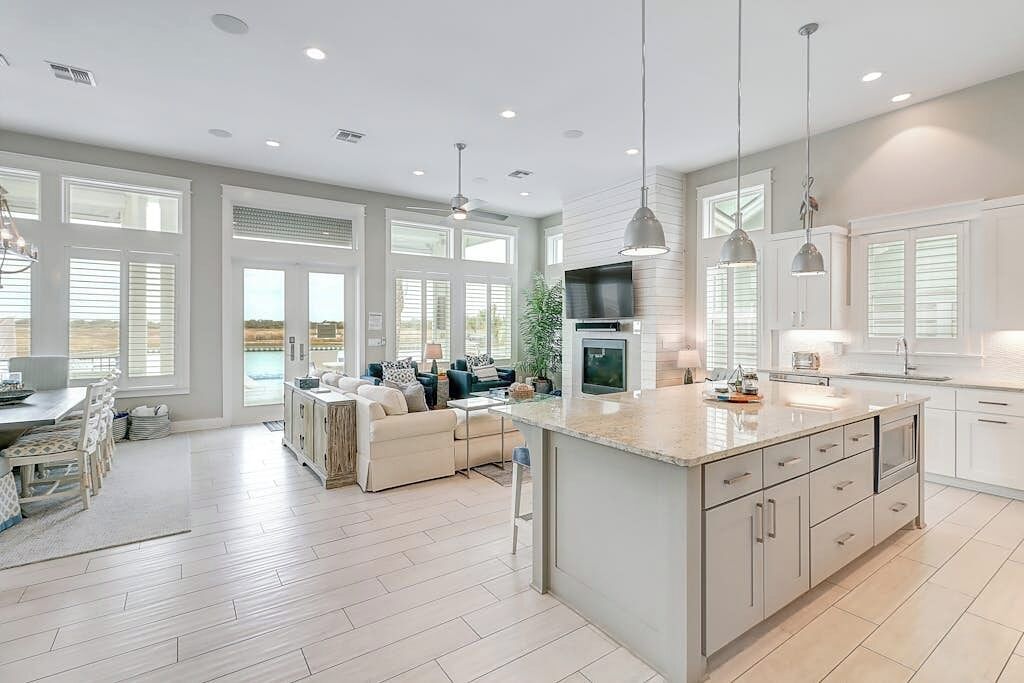 A spacious kitchen with a large island, modern pendant lighting, and a dining area with a sofa and chairs.