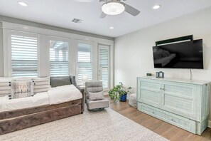 A bedroom with a bed, a chair, a dresser, and a television. - Waterfront Paradise | Private Pool & Dock, Poolside TV & Multi-TV Game Room (Rockport)