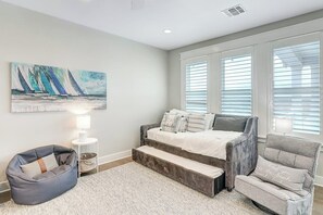 A bedroom with a bed, a bean bag chair, a side table, and a painting on the wall. - Waterfront Paradise | Private Pool & Dock, Poolside TV & Multi-TV Game Room (Rockport)
