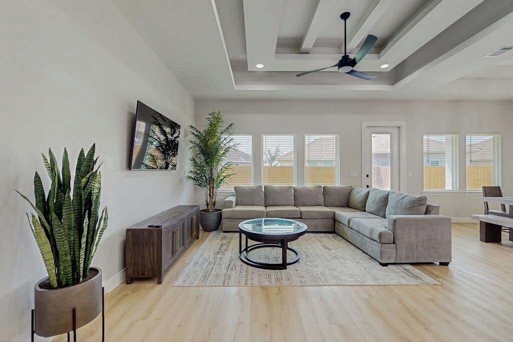 A spacious living room with a sectional sofa, a coffee table, and a ceiling fan.