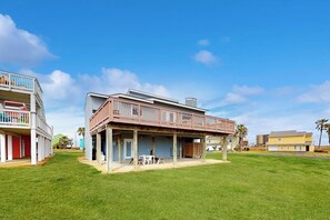 Een twee verdiepingen tellend huis met een balkon, een overdekte patio en een gazon.