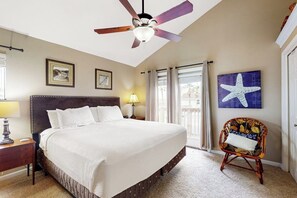Ein Hotelzimmer mit einem großen Bett, einem Deckenventilator, einem Sessel mit Kissen und einem Kunstwerk mit einem Seestern an der Wand.