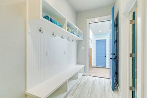 Un couloir avec un banc blanc, un porte-manteau et une porte bleue.