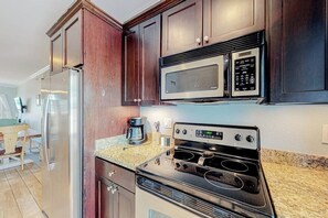 A kitchen with a stainless steel refrigerator, a microwave, and an oven. - Dawn Beach Condominiums #323 (Galveston)