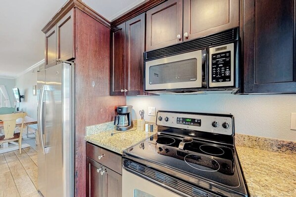 A kitchen with a stainless steel refrigerator, a microwave, and an oven. - Dawn Beach Condominiums #323 (Galveston)