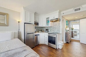 A compact kitchen with white cabinetry, a built-in oven, and a dishwasher. - Sunset Dream - Gulf-Front, Pools & Pickleball (Galveston)
