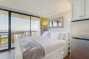 Ein Schlafzimmer mit einem Bett, einem Spiegel, einem Kühlschrank und einem Balkon mit Blick.