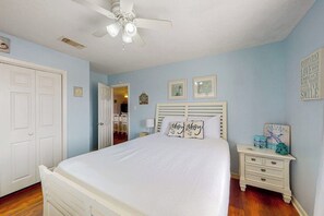 A bedroom with a bed, a nightstand, a dresser, and a ceiling fan. - Captain's Quarters - Walk to the Beach, Patio (Galveston)