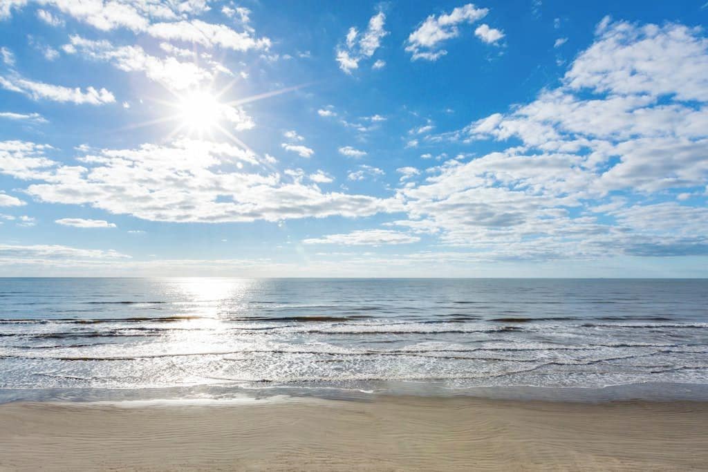 A beach with a clear sky and sunlight reflecting on the water.