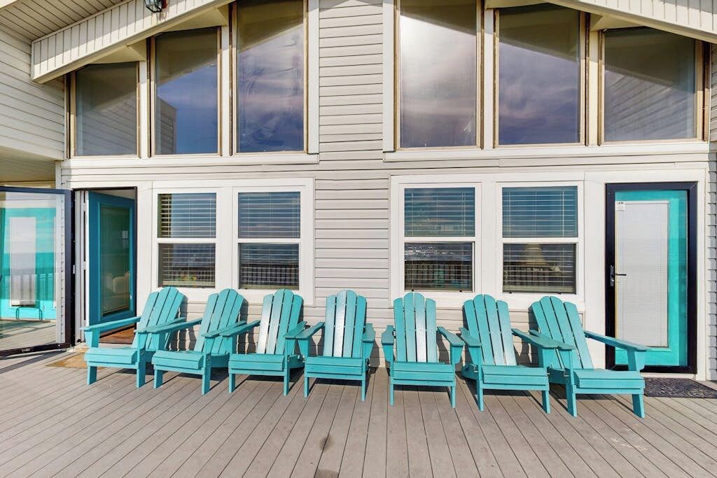 A building with multiple windows and a deck area with several chairs.