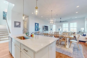 A spacious living area with a kitchen island, dining table, and seating arrangements. - Sunset Bay - Bay Views, 2 Balconies, Sleeps 12 (Galveston)