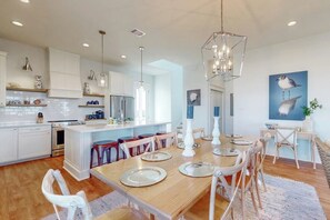 A modern kitchen with white cabinetry, a central island, and pendant lighting. - Sunset Bay - Bay Views, 2 Balconies, Sleeps 12 (Galveston)
