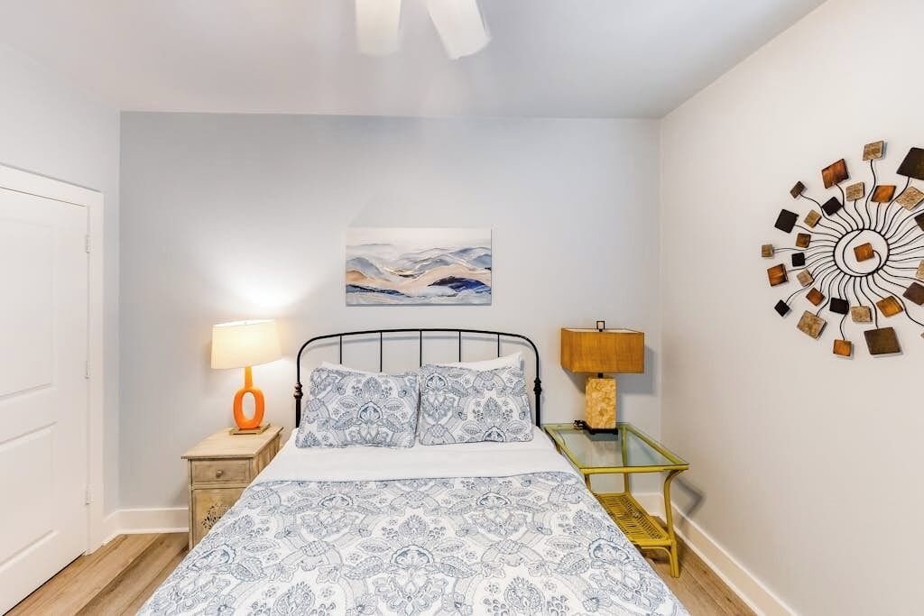 A bedroom with a bed, two bedside tables, a wall art piece, and a decorative wall hanging.