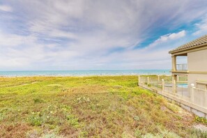 Ein Objekt direkt am Strand mit Blick auf das Meer, einer Rasenfläche und einem Gebäude mit Balkon.