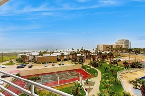 A residential area with a tennis court, a parking lot, and a view of the ocean. - Sunchase IV #311 - 2 Balconies & Heated Pools (South Padre Island)