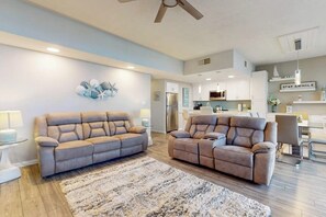 Un salon moderne avec deux canapés, un tapis et un ventilateur de plafond.