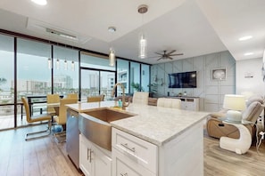 A modern kitchen with a central island, large windows, and a city view. - Sunchase IV #311 - 2 Balconies & Heated Pools (South Padre Island)