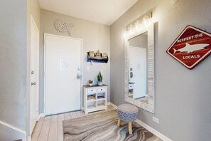 A hallway with a white door, a small bench, a mirror, and a sign that says 'RESPECT THE LOCALS' with a shark silhouette. - Sunchase IV #311 - 2 Balconies & Heated Pools (South Padre Island)
